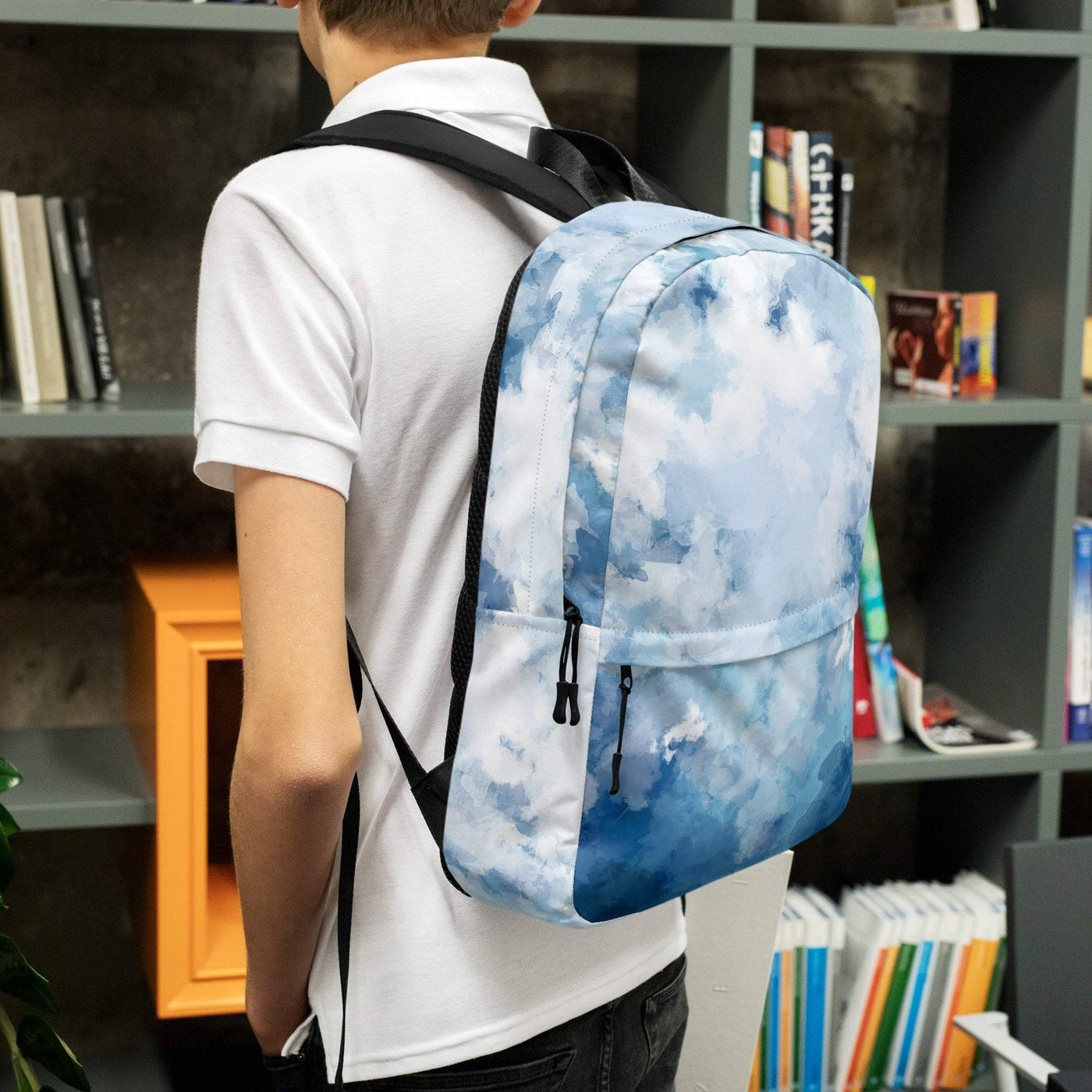 Person wearing a blue and white water-resistant backpack with multiple zippered pockets in a room with bookshelves