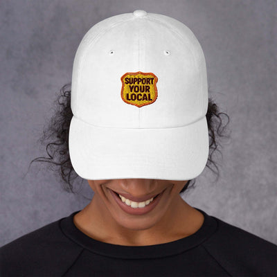 White low-profile dad hat with "Support Your Local" embroidered patch and adjustable strap.