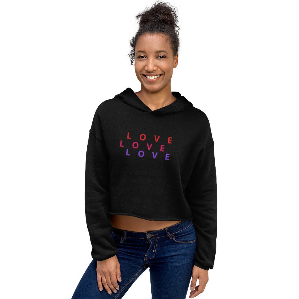 Black crop hoodie with "LOVE" printed in red and purple, featuring raw hem and dropped shoulder cut.